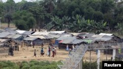 FILE - Rohingya people who fled from their towns after violence in the state of Rakhine are seen behind a fence on the border line outside Maungdaw, Myanmar, March 31, 2018. 