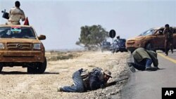 Libyan rebels duck while others retreat during an exchange of fire with pro Gadhafi forces along the frontline at the outskirts of Brega, Apr 4 2011