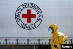 Seorang spesialis mengenakan APD, ikut ambil bagian dalam disinfeksi konvoi truk Komite Palang Merah Internasional (ICRC) dan Perserikatan Bangsa-Bangsa (PBB), yang membawa peralatan medis dan obat-obatan ke wilayah Donetsk yang dikuasai pemberontak di tengah pandemi COVID-19, di pos pemeriksaan di pemukiman Olenivka, Ukraina 3 April 2020. (REUTERS/Alexander Ermochenko)