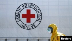 FILE: A specialist takes part in the disinfection of a truck convoy of the International Committee of the Red Cross (ICRC) and the United Nations (UN), at a check-point in the settlement of Olenivka, Ukraine. Taken April 3, 2020