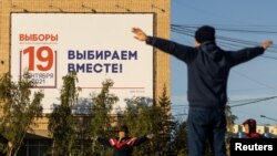 People do exercises in front of an election poster ahead of parliamentary elections in Yakutsk, Russia, Sept. 7, 2021. 