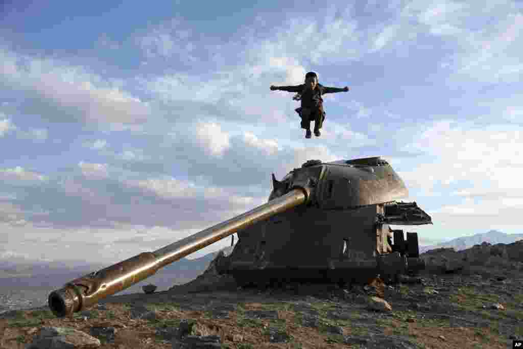 A boy jumps off the turret of a Soviet tank on a hilltop on the the outskirts of Kabul, Afghanistan.