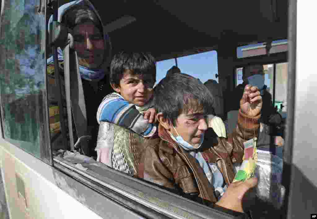 Two Yazidi boys, suffering from several infections from mosquito bites while held by the Islamic State group, wait with their mother inside a bus before being driven to the Kurdish city of Dohuk, in Alton Kupri, outside Kirkuk, Iraq. The Islamic State group released about 200 Yazidis, mostly elderly, held for five months in Iraq.