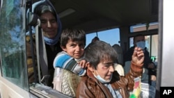 Two Yazidi boys, suffering from several infections from mosquito bites while held by the Islamic State group, wait with their mother inside a bus before being driven to the Kurdish city of Dohuk, in Alton Kupri, outside Kirkuk, Iraq, Jan. 18. 2015. 