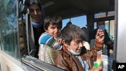 Two Yazidi boys, suffering from several infections from mosquito bites while held by the Islamic State group, wait with their mother inside a bus before being driven to the Kurdish city of Dohuk, in Alton Kupri, outside Kirkuk, Iraq, Jan. 18. 2015. 