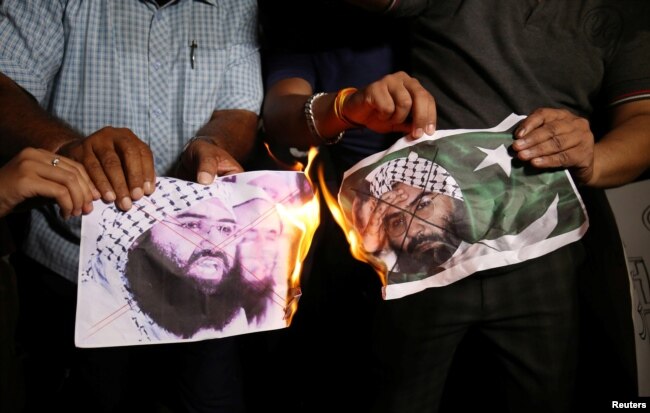 People burn pictures of Masood Azhar, the head of a Pakistan-based militant group Jaish-e-Mohammad, as they celebrate the U.N. Security Council committee's decision to blacklist Azhar, in Ahmedabad, India, May 1, 2019.