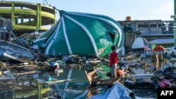 Seorang penyintas bencana gempa bumi berusaha menyelamatkan barang-barang yang masih bisa dipakai di sebuah masjid yang roboh di Palu, Sulawesi Tengah, 1 Oktober 2018.