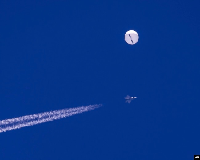 FILE - In this photo provided by Chad Fish, a large balloon drifts above the Atlantic Ocean, just off the coast of South Carolina, with a fighter jet and its contrail seen below it, Saturday, Feb. 4, 2023. The balloon was struck by a missile from an F-22 fighter just off Myrtle Beach, fascinating sky-watchers across a populous area known as the Grand Strand for its miles of beaches that draw retirees and vacationers. (Chad Fish via AP)