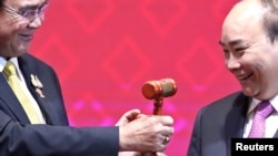FILE - Vietnam's Prime Minister Nguyen Xuan Phuc takes the gavel from Thai Prime Minister Prayuth Chan-Ocha who hands over the ASEAN chairmanship to Vietnam during the closing ceremony of the 35th ASEAN Summit and related summits in Bangkok, Nov. 4, 2019.