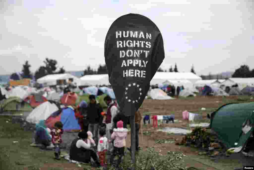 Một biểu ngữ có nội dung &ldquo;Nhân quyền không áp dụng ở đây&rdquo; được những nhà hoạt động phủ lên một biển báo ven đường tại một trại tạm cư dành cho những người tị nạn và di dân ở biên giới Hy Lạp-Macedonia, gần làng Idomeni của Hy Lạp, ngày 17 tháng 3, 2016.