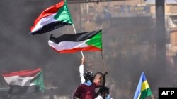 Des manifestants soudanais brandissent des drapeaux nationaux alors qu'ils participent à une manifestation dans la ville de Khartoum Bahri, la ville jumelle nord de la capitale, pour exiger la transition du gouvernement vers un régime civil, le 21 octobre