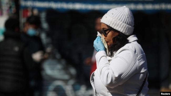 FILE - A woman blows her nose in Dalston as the spread of the coronavirus disease (COVID-19) continues, London, Britain, April 14, 2020. (REUTERS/Hannah McKay)