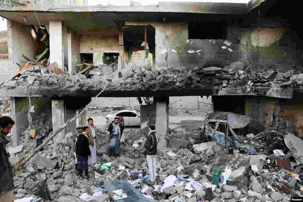 Guards stand on the rubble of a house hit by Saudi-led air strikes in Sanaa, Yemen.