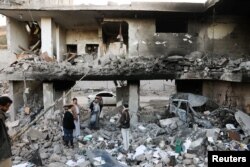 Guards stand on the rubble of a house hit by Saudi-led air strikes in Sanaa, Yemen, January 18, 2022.