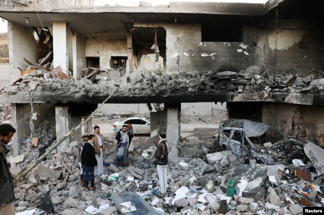 Guards stand on the rubble of a house hit by Saudi-led air strikes in Sanaa, Yemen, January 18, 2022.