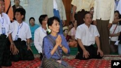Burmese democracy icon Aung San Suu Kyi, center, pays her respects to a senior Buddhist monk during her visit to a Buddhist monastery in Bago, north of Rangoon, Burma, August 14, 2011