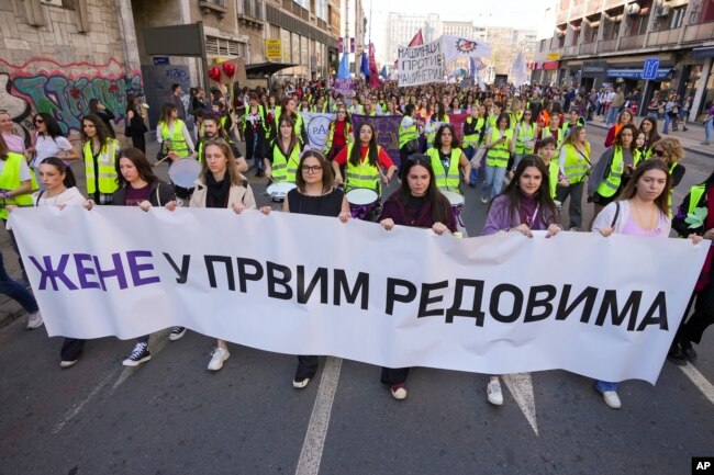 Mujeres sostienen una pancarta que dice: "Mujeres en las primeras filas" durante una marcha en apoyo a las mujeres en el Día Internacional de la Mujer en Belgrado, Serbia, el sábado 8 de marzo de 2025. (Foto AP/Darko Vojinovic)