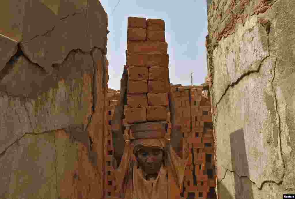 A female laborer carries bricks at a brick factory on the outskirts of the southern Indian city of Chennai. May Day or Labour Day will be marked on May 1. 