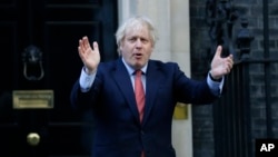 Britain's Prime Minister Boris Johnson applauds on the doorstep of 10 Downing Street in London during the weekly "Clap for our Carers" Thursday, May 28, 2020. The COVID-19 coronavirus pandemic has prompted a public display of appreciation for care…