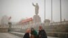 Ethnic Uighurs sit near a statue of China's late Chairman Mao Zedong in Kashgar, Xinjiang Uighur Autonomous Region, China, March 23, 2017. 