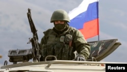 FILE - An armed man, believed to be a Russian serviceman, stands guard outside a Ukrainian military base in Perevalnoye, near the Crimean city of Simferopol, March 14, 2014. Authorities released RFE/RL journalist Nikolai Semena on bail, but with travel restrictions, according to a report quoting his lawyer, April 19, 2016.