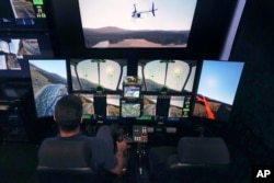 Joao Magioni, Chief Flight Officer of Rotor Technologies, flies a simulated unmanned semi-autonomous helicopter from the company's remote operations center, Monday, Nov. 11, 2024, in Nashua, N.H. (AP Photo/Charles Krupa)