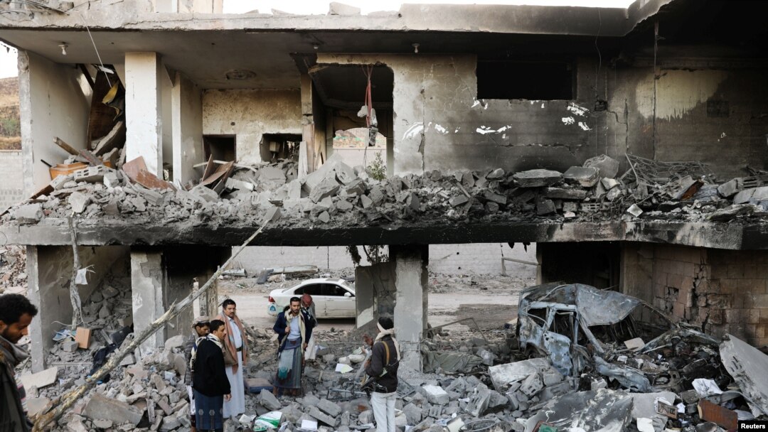 Guards stand on the rubble of a house hit by Saudi-led air strikes in Sanaa, Yemen, January 18, 2022. 