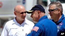 Mark Kelly, centro, habla con su hermano gemelo Scott, izquierda.