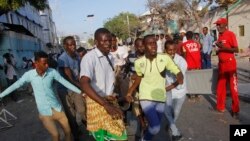 Somalis help a wounded civilian after a car bombing in Mogadishu, Somalia, March 22, 2018. 