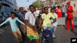 Des civils aident un blessé à Mogadiscio, Somalie, le 22 mars 2018. 