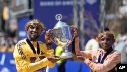 Sisay Lemma, of Ethiopia, left, winner of the men's division of the Boston Marathon, and Hellen Obiri, of Kenya, right, winner of the women's division of the race, hold the trophy on the finish line of the Boston Marathon, on April 15, 2024, in Boston.