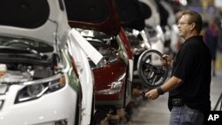 Assembly line worker Gary Phillips carries a steering wheel for a Chevrolet Volt at the General Motors Hamtramck Assembly plant in Hamtramck, Michigan, July 27, 2011.