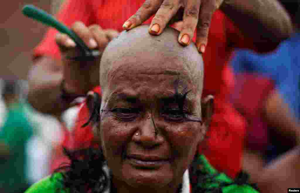 A supporter of Tamil Nadu Chief Minister Jayalalithaa Jayaraman gets her head shaved near Jayalalithaa&#39;s burial site in Chennai, India.