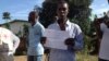 Osman Sesay, an Ebola survivor, holds up his discharge certificate in Banga Ground community, near Freetown, Sierra Leone, Sept., 27, 2014.