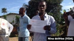 Osman Sesay, an Ebola survivor, holds up his discharge certificate in Banga Ground community, near Freetown, Sierra Leone, Sept., 27, 2014.