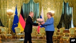 Russian President Vladimir Putin, left, presents flowers to German Chancellor Angela Merkel during their meeting in the Kremlin in Moscow, Russia, Aug. 20, 2021.