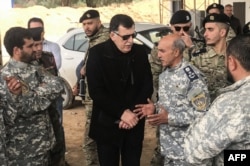 The head of Libya's U.N.-backed unity government, Fayez al-Sarraj, center, visits military and security commanders of the government forces who supervised recapture of the checkpoint 27 in Janzour, between Tripoli and the coastal town of Zawiya, April 5, 2019.