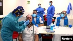 A man has a swab sample taken for a coronavirus disease antigen test at a cultural center in the working-class neighborhood of Vallecas in Madrid, Spain, Oct. 1, 2020. 