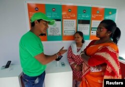 FILE - A WhatsApp-Reliance Jio representative explains how to use Facebook Inc's WhatsApp messenger to a woman during a drive by the two companies to educate users, on the outskirts of Kolkata, India, Oct. 9, 2018.