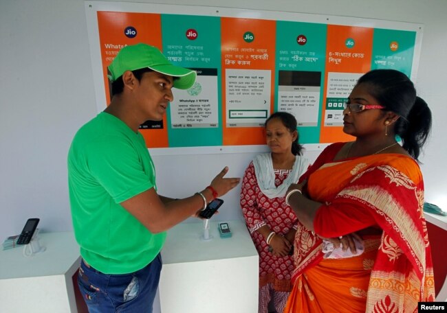 FILE - A WhatsApp-Reliance Jio representative explains how to use Facebook Inc's WhatsApp messenger to a woman during a drive by the two companies to educate users, on the outskirts of Kolkata, India, Oct. 9, 2018.