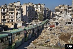 مشرقی حلب میں پھنسے شہریوں اور باغیوں کے انخلا کے لیے بسیں کھڑی ہیں