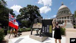 Paloma Wu holds a Black Lives Matter banner while calling for a new Mississippi state flag, while current flag supporters wave the flag as both sides make their sentiments known June 28, 2020. (AP Photo/Rogelio V. Solis)