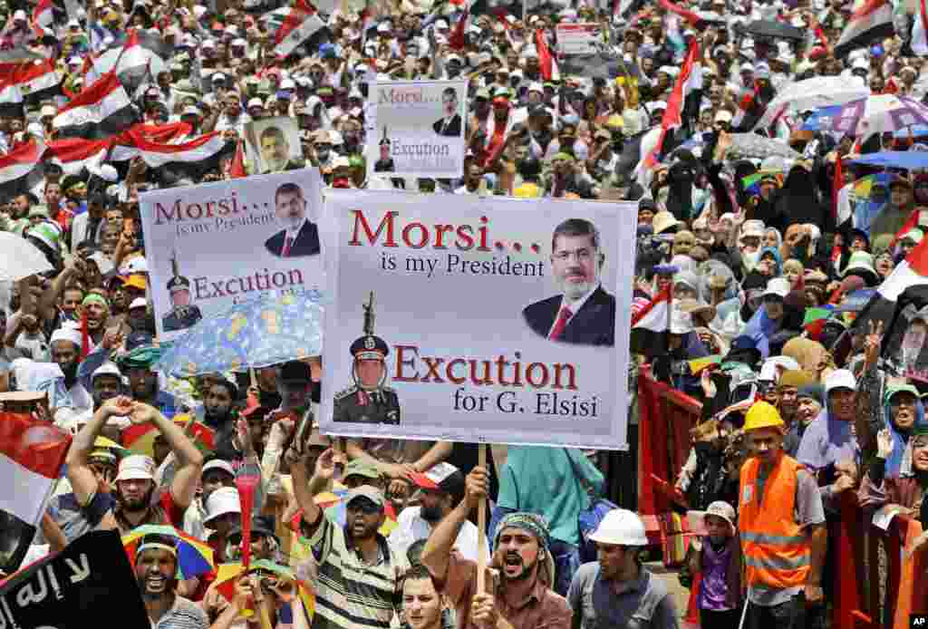 Supporters of Egypt&#39;s ousted President Mohammed Morsi hold up placards as they shout slogans during a demonstration where protesters have installed their camp, at Nasr City, Cairo, Egypt, July 19, 2013.&nbsp;