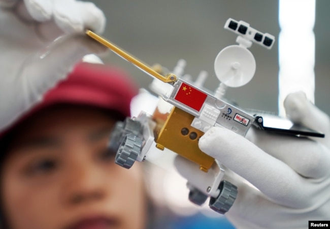 FILE - A worker inspects a scale model of the moon rover for China's Chang'e 4 lunar probe, at a factory in Dongguan, Guangdong province, China, Nov. 16, 2018.