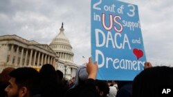 FILE - A woman holds up a sign outside the Capitol in support of the Deferred Action for Childhood Arrivals program, Dec. 5, 2017.