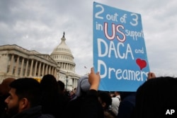 FILE - A woman holds up a sign outside the Capitol in support of the Deferred Action for Childhood Arrivals (DACA) program, Dec. 5, 2017, on Capitol Hill in Washington.