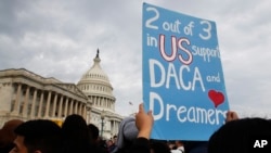 A woman holds up a sign outside the Capitol in support of the Deferred Action for Childhood Arrivals (DACA) program, Dec. 5, 2017, on Capitol Hill in Washington.