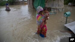 인도 아삼주 가우하티의 마을이 폭우로 인해 침수된 가운데 여성이 아이를 안고 대피하고 있다. 