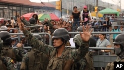 ARCHIVO - Un soldado pide calma a los amigos y familiares de los reclusos que buscan información tras los mortales enfrentamientos en la Penitenciaría del Litoral, en Guayaquil, Ecuador, el 25 de julio de 2023.