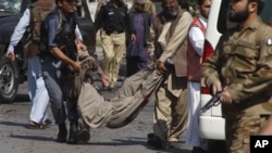 Nhân viên cứu hộ và cảnh sát Pakistan khiêng tử thi ra khỏi hiện trường vụ đánh bom tự sát ở Peshawar, ngày 29/3/2013.